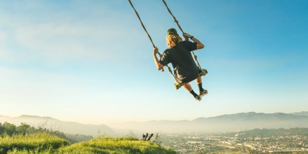 Some guy on a swing with a spectacular vista.